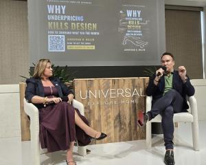 Johnathan H. Miller speaking into a microphone on stage beside Jessica Duce, with the Why Underpricing Kills Design book cover on the screen behind them at High Point Market