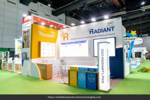 White and yellow RADIANT booth with backlit panels, three colored product pedestals and an illuminated upright sign.