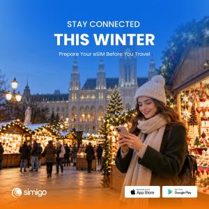 A traveler using a smartphone at Vienna’s Christmas market, with festive stalls, Christmas lights, and Vienna City Hall in the background, alongside Simigo branding.