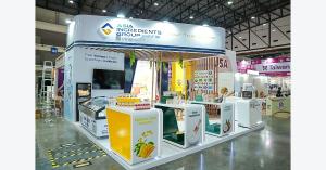Asia Ingredients Group booth with white fascia, yellow product counter and ingredient displays