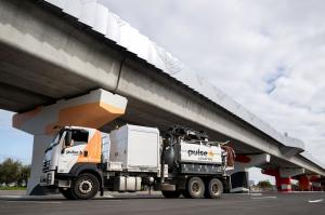 Pulse Locating vacuum excavation truck parked beneath an elevated concrete rail line