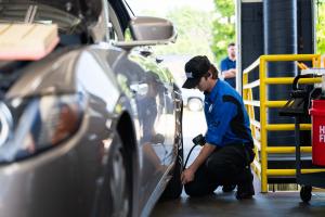 Strickland Brothers technician checks tire pressure on a gray vehicle inside a service bay while performing a ten minute oil change..