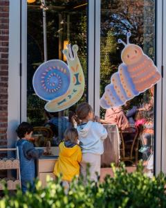 Children free play at a play kitchen, with the caterpillar and snail from Carrie the Tree Fairy, at One Wild's "Books, Bread & Beats!" event.