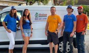 Gator Leak Detection team standing in front of a branded service van, wearing company shirts and caps.