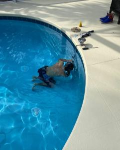 Technician inspecting a swimming pool drain and plumbing fittings during a pool leak detection service