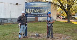 Two Planet Networks employees happily standing next to the Matamoras Welcome Sign.