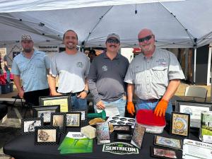 M&M Pest Control owner Cliff McBroom and team members at an outdoor community event booth in Palestine, Texas