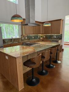Custom kitchen with wood cabinetry, natural stone backsplash and island, and copper pendant lights