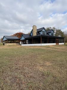 Single-story metal-sided home with pergola on a newly graded East Texas building site