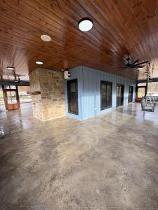 Screened porch with stone fireplace, stained wood ceiling and stained concrete floor