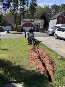 WaterWise Plumbing technician operating a trencher to install a residential water line