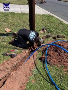 Plumber connecting blue PEX water service line in a residential front yard