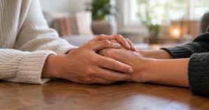 Two people holding hands across a table in support during alcohol and drug addiction recovery