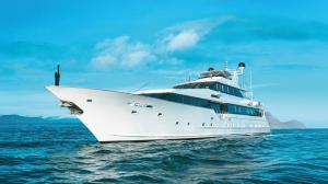 White Galaxy Stella expedition yacht viewed from the front and side on blue ocean waters, with mountainous islands in the background.