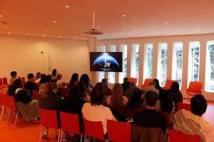Students in a darkened auditorium watching the documentary on a large screen