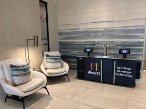 iPourIt self-pour kiosk with four taps, two touchscreens, and a blue custom wrap in a hotel lobby concept rendering.