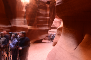 Photographers with cameras and tripods inside Antelope Canyon, surrounded by towering red sandstone walls and winding canyon passages in Page, Arizona.