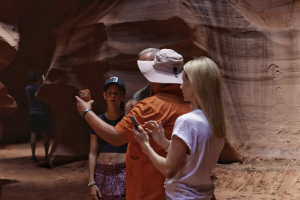 Visitors taking photos and exploring the curved red sandstone walls inside Antelope Canyon during a guided sightseeing experience in Page, Arizona.