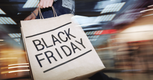 A stylized, blurred background expressing speed of movement, with a shopper holding a paper bag with "BLACK FRIDAY" on it while walking in a store