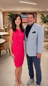Debbie Danto, Owner and COO, and Craig Danto, CEO of Danto Builders, standing together and smiling in a modern lounge with an American flag on the wall behind them.