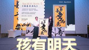 Kerry Guo receiving a framed calligraphy piece on stage at the live auction