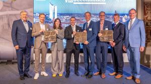 Award winners and dignitaries, including Lord Mayor Burkhard Jung alongside Appsfactory CTO Rolf Kluge and COO Dr. Roman Belter, standing on stage with commemorative plaques at the Via Oeconomica ceremony in Leipzig.