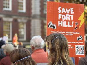Two protesters holding a bright orange sign that says "Save Fort Hill" on Smith College's campus during a protest against the planned closure of the early childhood center on Wednesday, October 28, 2026.