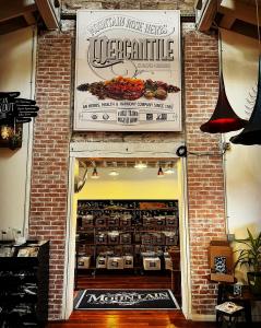 Image features the signage and displays inside the Mountain Rose Herbs Mercantile Eugene. A large sign displayed above a red brick trimmed doorway that states "Mountain Rose Herbs Mercantile Eugene Oregon. An Herbs, Health, & Harmony Company Since 1987".