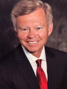 Professional headshot and portrait of Dr. Mark T. Saunders, M.D., smiling in a dark suit jacket and red tie.