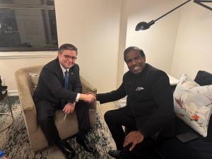 Speaker Mike Johnson and Dr. K. A. Paul seated together and shaking hands during a meeting focused on leadership, dialogue and peace