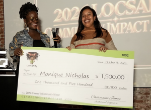 LOCnificent founder Lovaeta Amoako and Crowned in Community Award winner Monique Nicholas smile while holding an oversized $1,500 Locsanity award check at LOCnificent 2026.
