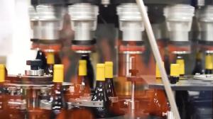Wine bottles with yellow closures moving through automated bottling equipment.