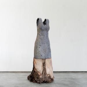 Kathy is a sculpture of a dress that is made of wood and ceramic and is grey and beige. Kathy stands 64" tall , 25" wide and 21" deep