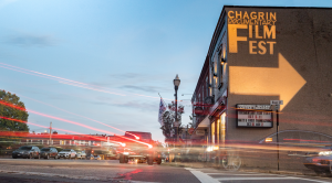 In the village of Chagrin Falls, cars drive by an illuminated sign that reads: Chagrin Documentary Film Festival
