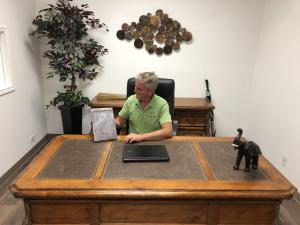 Sr. Project Manager Keith Campbell for McAllen Valley Roofing Co. inside his office showing a copper roof tile.