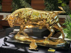 Gold Bull by Lorenzo Ghiglieri on display shining in lustrous gold plated bronze at the Monterey Car Show Week 2019 with spotlight lighting