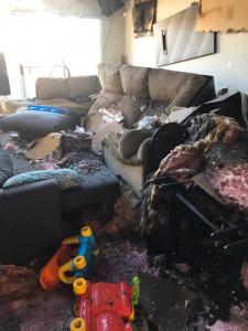 A destroyed living room full of debris, burned furniture, and melted children's plastic toys