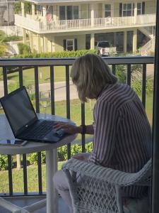 A picture showing Deb Cake Fortin, the author of UP PERISCOPE writing and enjoying a glass of wine at the same time