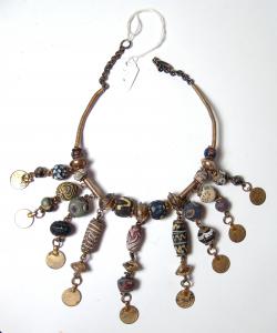 Decorative antique necklace comprised of Islamic glass beads, mostly circa 8th-12th century AD, with the beads strung together with plated coin replicas, brass breads and wire (est. 700-$1,000).