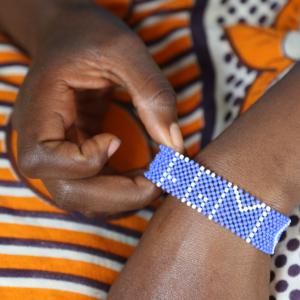 Gros plan du poignet d'une femme portant un bracelet en perles disant MGF.