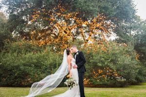 Bride and groom kissing under the lit, live oak tree on the property's meadow.