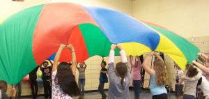 Kids play a parachute game in PE class at a Lansing School