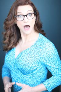 red haired white woman with blue dress with polkadots with arms like she is running and face looks suprised with mouth open a little bit