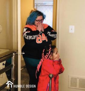 This mother and her little girl have their hands over their mouths as they look at their newly furnished space.