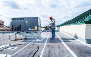 McAllen Valley Roofing Co. crew member spraying silicone on a commercial flat roof.