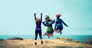 Empowered women jumping near a gorgeous blue ocean