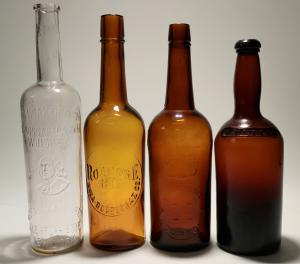 Set of four 1800s bourbon and whiskey bottles, including a rare J. Moore Brown Old Bourbon, a Roanoke Rye brown, a blob top brown and a clear Old Quaker Club Whiskey (est. $350-$1,000).
