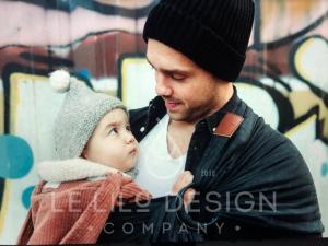 Vater trägt Tochter in schwarzem Leinen-Babytragetuch von LE Lilo Design vor coolem Hintergrund.