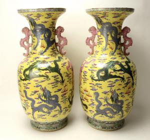 Dramatic and monumental pair of yellow dragon palace vases, each one 28 inches tall, boasting multicolored dragons swirling among flaming clouds and pearls (est. $3,000-$5,000).