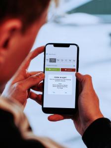 Person holding smart phone and using the SMARTcare COVID-19 Toolset